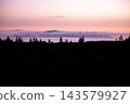 Cloud sea and distant island under a pink evening sky. The cloud sea and the dark shape of a neighbouring island sit under a pink evening sky in Teide National Park. Island distance and calm for trave 143579927