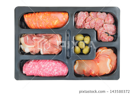 Variety semi-dry sausages in slices in a black container. Raw cured sausages on a white background. Top view. Variety semi-dry sausages in slices in a black container. Raw cured sausages on a white background. Top view. 143580372