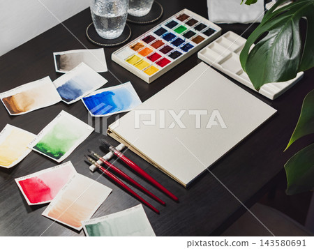 Professional watercolor swatches artist workspace setup. Watercolor swatches artist workspace with blank paper sheet and brushes. Clean watercolor swatches artist workspace displays painting 143580691
