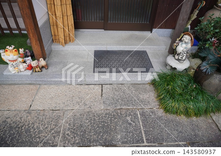 日式房屋的入口和石板路上，裝飾著招手的貓和信樂燒貉。 143580937