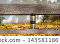 A stainless steel thermos and fresh pastry rest on a wooden bench covered with autumn leaves. The scene represents comfort and peaceful recreation. 143581186
