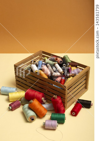 A box with multi colored coins of different threads on a colored background A box with multi colored coins of different threads on a colored background 143581739