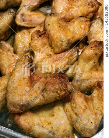 Fried chicken wings displayed in a supermarket deli, presenting cooked poultry arranged for sale in a grocery store prepared food section 143582090