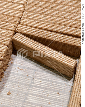Milk wafers stacked in neat rows inside a box displayed in a supermarket, showcasing sweet baked products arranged attractively for customers choosing from the selection 143582521