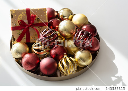 Overhead studio shot of golden and red Christmas baubles with a gift box on tray Overhead studio shot of golden and red Christmas baubles with a gift box on tray 143582815
