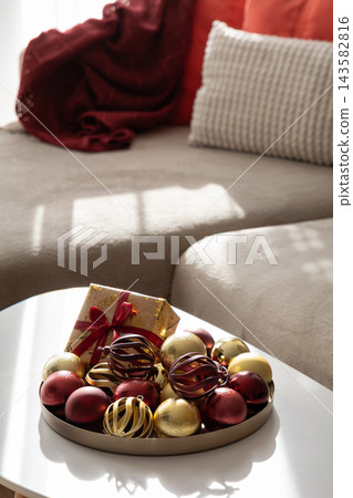 Cozy living room interior decorated for winter holidays with red and gold baubles Cozy living room interior decorated for winter holidays with red and gold baubles 143582816