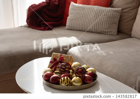 Cozy living room interior decorated for winter holidays with gift box and baubles Cozy living room interior decorated for winter holidays with gift box and baubles 143582817