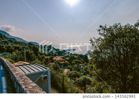 French Riviera town and coastline beneath wooded hills. 143582991