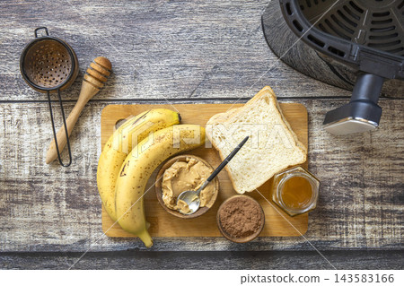 Ingredients for cooking toast bread with peanut butter and fried banana in kitchen gadget modern air fryer. Lifestyle trendy of new cooking. Ingredients for cooking toast bread with peanut butter and fried banana in kitchen gadget modern air fryer. Lifestyle trendy of new cooking. 143583166