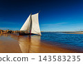 A sailboat with white sails in the beach of the Baltic sea 143583235