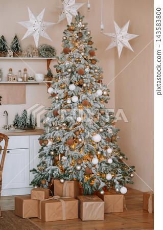 Beautiful decorated Christmas tree with ornaments and wrapped gift boxes in cozy room interior 143583800