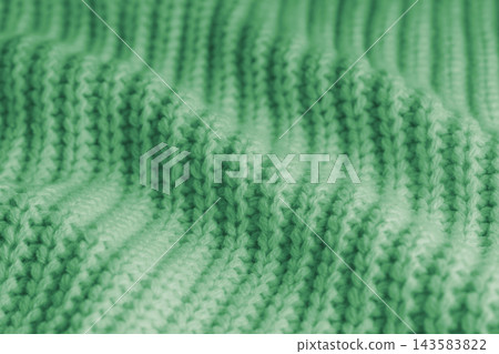 Soft green knitted sweater texture with chunky yarn and raised stitches, waves and gentle folds Soft green knitted sweater texture with chunky yarn and raised stitches, waves and gentle folds 143583822