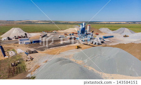Industrial site with machinery and sand piles in open landscape during daytime Industrial site with machinery and sand piles in open landscape during daytime 143584151