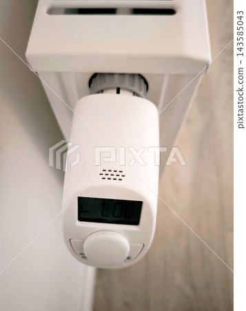 Digital thermostat on a white radiator with LOC and day of the week indicator. Top view. Digital thermostat on a white radiator with LOC and day of the week indicator. Top view. 143585043