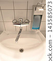 Modern faucet and sanitizer dispenser over a white sink 143585073