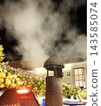 Smoke billows from a chimney at the evening Christmas market. A cozy and festive atmosphere. 143585074
