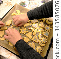 Children's hands decorate raw cookies with stars and sprinkles. 143585076