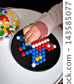 Educational game. A child assembles a colorful mosaic on a black board. 143585077
