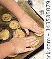 Children's hands placing homemade chocolate chip cookies on a baking sheet 143585079