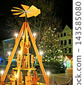 Wooden Christmas pyramid against the silhouettes of houses 143585080