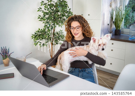 Woman working remotely at home with pet dog 143585764