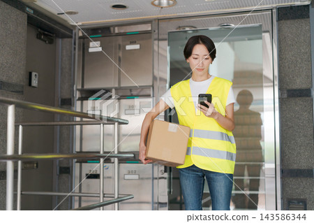 一名女子向公寓大樓送貨 一名女子向公寓大樓送貨 143586344