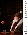 Elegant Santa examining red Christmas ornament at bar 143587216