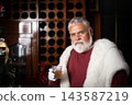 Elegant Santa posing behind bar with holiday drinks 143587219