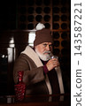Elegant Santa in winter hat holding warm drink at bar 143587221