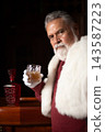 Santa holding glass of amber drink at elegant bar 143587223