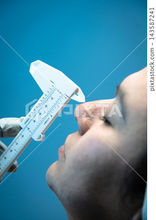 Close-up of caliper measuring patient's nose profile Close-up of caliper measuring patient's nose profile 143587241