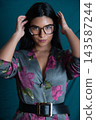 Woman posing wearing glasses and floral dress adjusting her hair 143587244