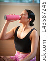 Woman drinking water from pink bottle practicing yoga 143587245