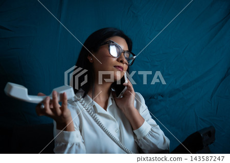 Young woman multitasking with modern and vintage phone Young woman multitasking with modern and vintage phone 143587247