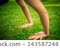 Person's hands touching green grass, feeling nature 143587248