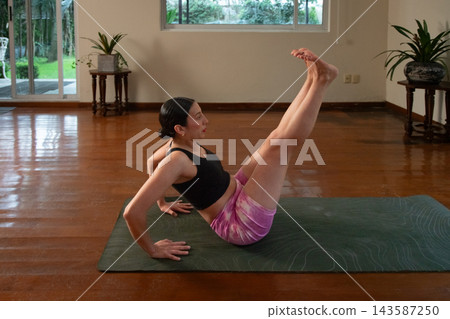 Woman doing boat pose yoga at home Woman doing boat pose yoga at home 143587250