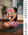 Woman drinking water from bottle after yoga workout at home 143587251