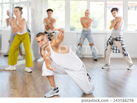 Young guy dancing hip-hop against background of group members Young guy dancing hip-hop against background of group members 143588256