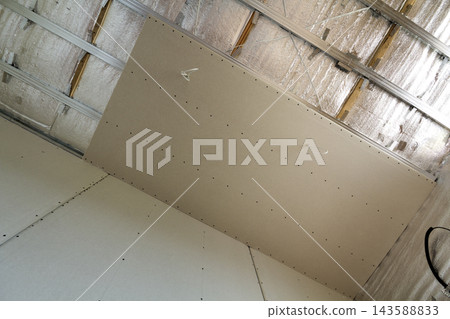 Room under construction with silver aluminum insulation foil and drywall on walls and ceiling. Room under construction with silver aluminum insulation foil and drywall on walls and ceiling. 143588833