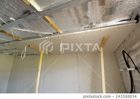 Room under construction with silver aluminum insulation foil and drywall on walls and ceiling. Room under construction with silver aluminum insulation foil and drywall on walls and ceiling. 143588834