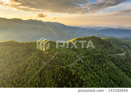 Road trip travel in Appalachian mountains near Mount Mitchell at sunset. Car driving on parkway through woods nature in summer season. Colorful forest in Tennessee Road trip travel in Appalachian mountains near Mount Mitchell at sunset. Car driving on parkway through woods nature in summer season. Colorful forest in Tennessee 143588840