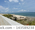A coastline stretching out under a blue sky and clear sea, and concrete blocks. 143589238