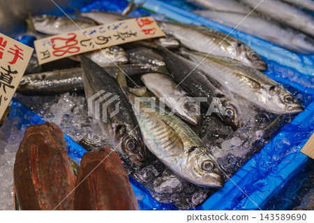 Fresh horse mackerel lined up on ice in a fish shop, with handwritten price tags. Fresh horse mackerel lined up on ice in a fish shop, with handwritten price tags. 143589690