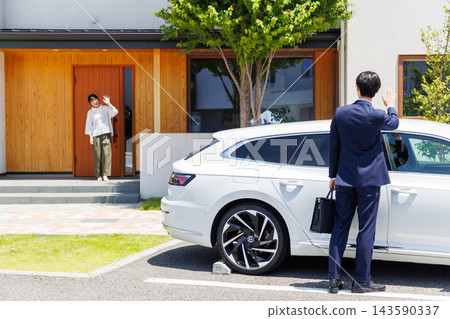 A wife sees her husband off as he leaves in his car. A wife sees her husband off as he leaves in his car. 143590337