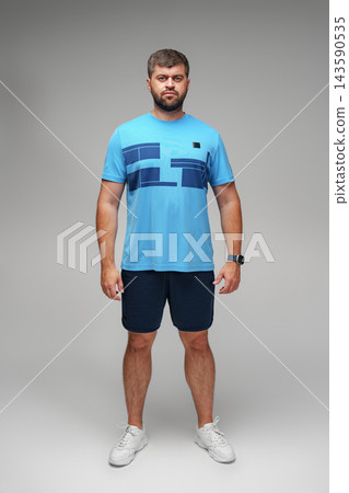 Man stands in blue athletic outfit with contrasting design in a studio setting during the daytime Man stands in blue athletic outfit with contrasting design in a studio setting during the daytime 143590535