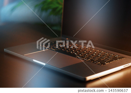 Laptop on a table with soft lighting in a workspace during evening hours Laptop on a table with soft lighting in a workspace during evening hours 143590637