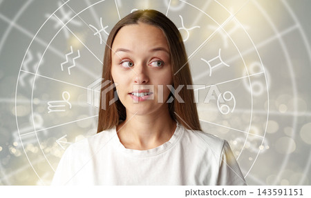 Astrology zodiac signs with a young woman in front of astrological symbols and a glowing background 143591151