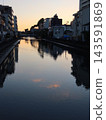 A river in the city where the sunset is reflected on the water's surface. 143591869