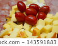 Gourmet appetizer platter presenting neatly rolled ham slices, cubed cheese, and vibrant red cherry tomatoes. Ideal for Eve celebrations 143591883