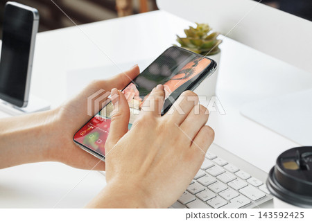 Using a smartphone for social media chats and calls at a desk with a keyboard and coffee cup Using a smartphone for social media chats and calls at a desk with a keyboard and coffee cup 143592425